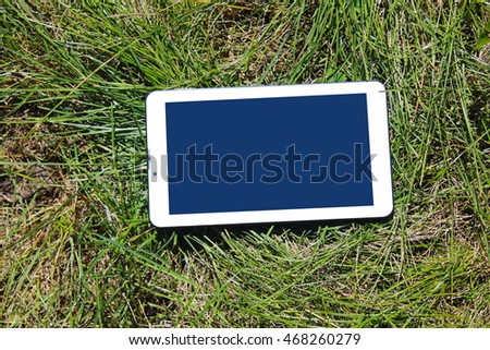 Digital tablet on the green grass