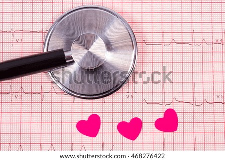 Hearts of paper and medical stethoscope lying on electrocardiogram graph, ecg heart rhythm, medicine and healthcare concept