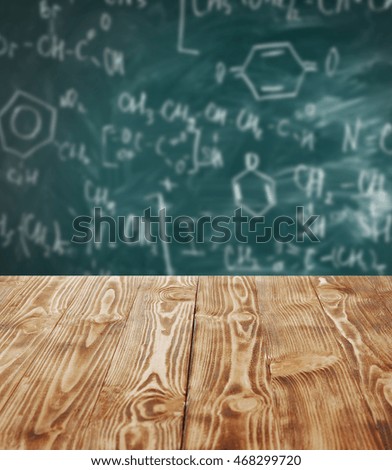 Wooden table on blackboard background. School concept.