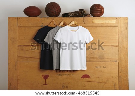 Basic vintage blank cotton t-shirts - charcoal, black and white, presented on cargo box backroungand various gaming balls and sport shoes on top
