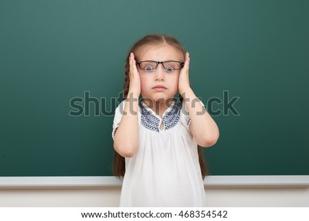 school student girl posing at the clean blackboard, grimacing and emotions, dressed in a black suit, education concept, studio photo