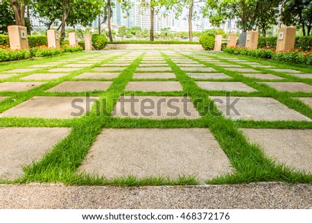 Pattern of square cement floor tiles with green grass blackground