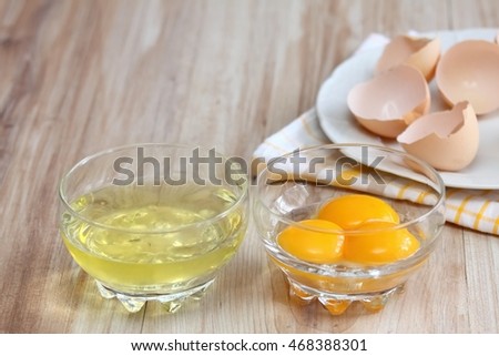 Separated egg white and yolks into two bowls and broken egg shells  are at background  Royalty-Free Stock Photo #468388301
