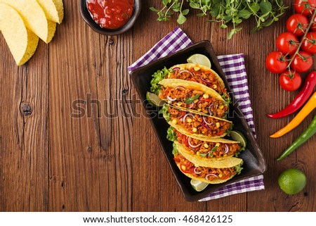 Few portion of tacos with meat and vegetables on wooden board