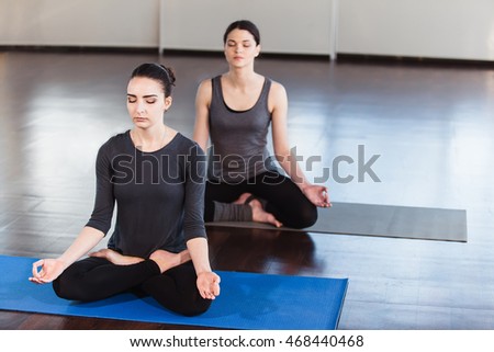 Two young women doing yoga in the fitness room. 
