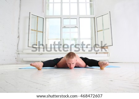 Sporty man practicing yoga. Asana Kurmasana. Tortoise pose. Tortoise posture. 