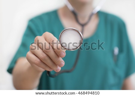 Female doctor holding stethoscope pointed toward camera, stock photo