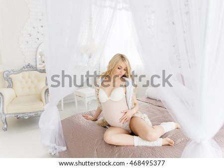 Beatiful pregnant woman in pink dress at the bedroom