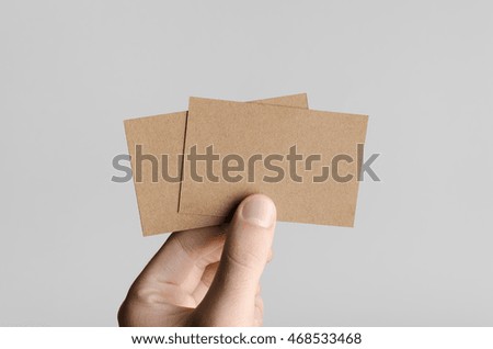 Kraft Business Card Mock-Up (85x55mm) - Male hands holding kraft cards on a gray background.