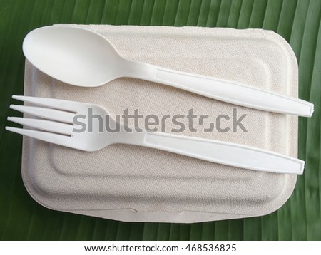 biodegradable lunch box made from bagasse with bio plastic spoon and fork on banana leaf