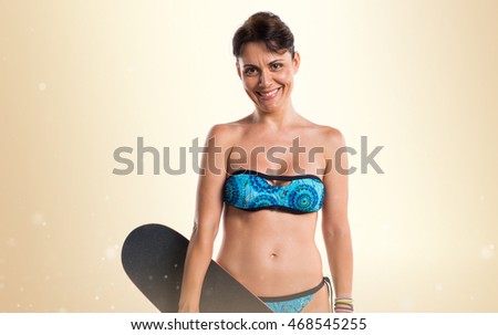 Woman in blue bikini with skate over ocher background