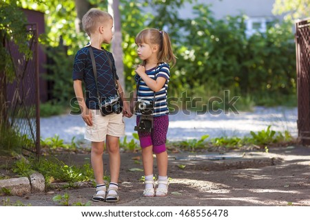 Little boy and a little girl wit two vintage cameras standing together holding hands