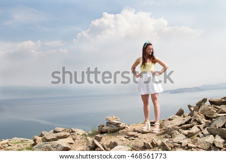 Beautiful young girl standing on a high mountain in the background of Lake Baikal