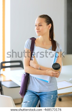 Smiling student with folders and cup of coffee