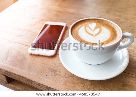 Coffee cup and mobile phone on wood table background, fillter effect, selective focus