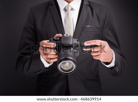Young photographer man holding camera isolated on black background