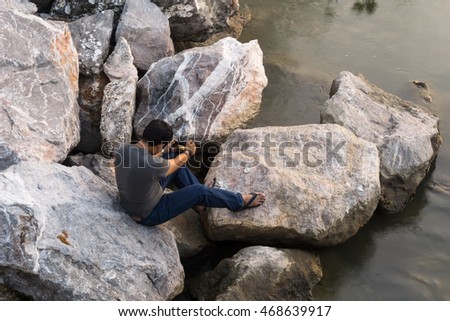 photographer sit on the rock and taking a picture