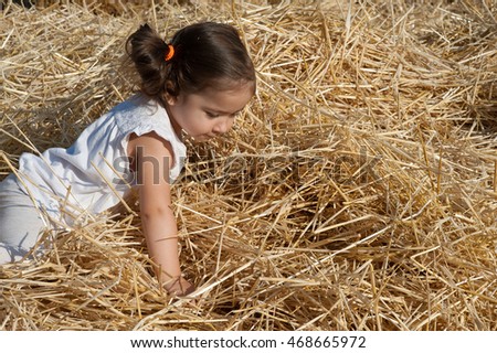 beautiful little girl lying in a haystack