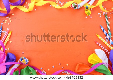 Happy Birthday background with decorated borders with party decorations on a bright orange wood table with copy space for your text here. 
