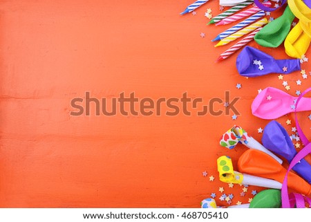 Happy Birthday background with decorated borders with party decorations on a bright orange wood table with copy space for your text here. 