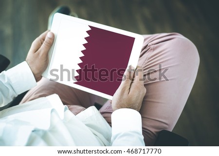 People using tablet pc and showing on the screen the flag of QUATAR