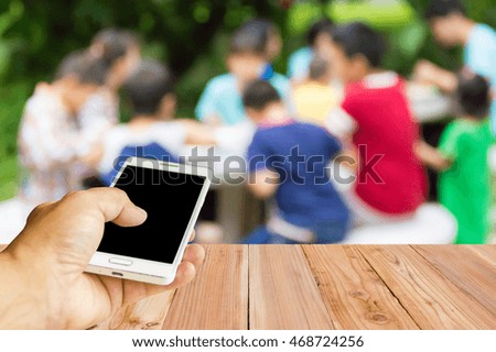 Man use mobile phone, blur image of children are eating as background.