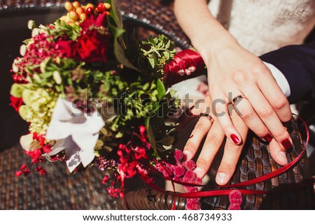 Hands of the groom and the bride with wedding rings near bouquet