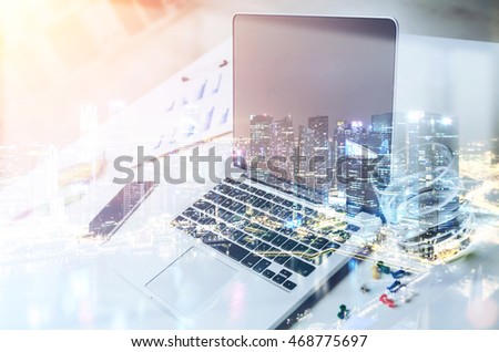 Laptop and smart phone on desk. Big city in background. Concept of corporate work. Toned image. Double exposure