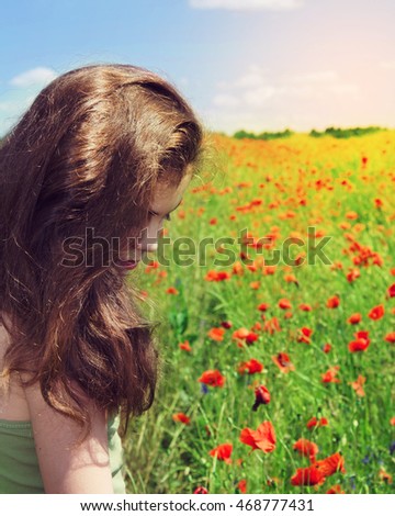 Beauty girl outdoors enjoying nature. Beautiful teenage model girl on the summer poppy field,sun light.