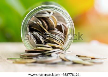 money in the glass on flare and green background, focusing coin.