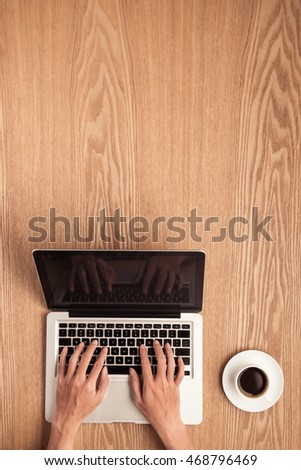 Hands using laptop  with coffee mug top view shot.