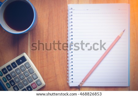 Notebook,coffee cup,calculator on wood background