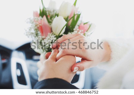 Hands of bride and groom with rings on wedding bouquet. Marriage concept