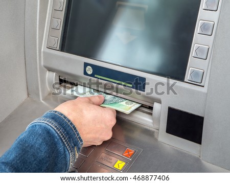 Closeup of woman's hand withdrawing cash from ATM slot