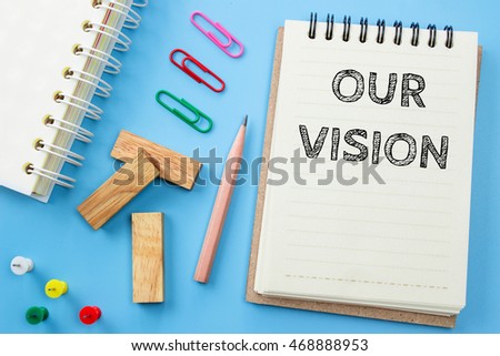 Text Our vision on white paper book and office supplies on blue desk / business concept