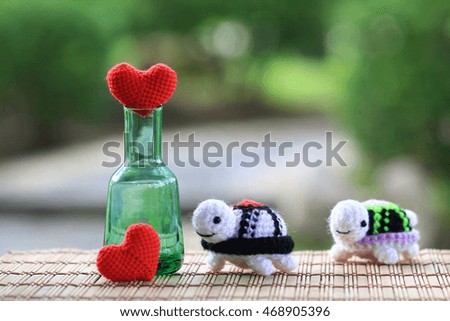 Handmade crochet heart and doll turtle on green background