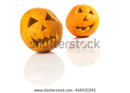 Food art creative concept. Halloween scary faces carved into yellow orange fruit isolated  over a white background.