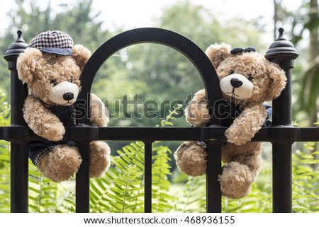 Teddy bears hanging on a fence in park with copy space, love and friendship concept in vintage style