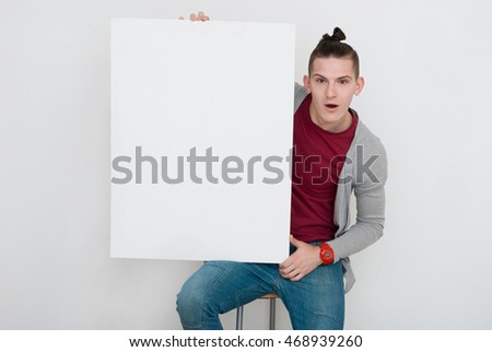 Happy young man showing and displaying placard ready for your text or product