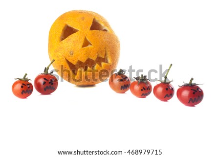 Food art creative concept. Halloween scary face carved into yellow orange fruit with sweet tomatoes monsters isolated over a white background