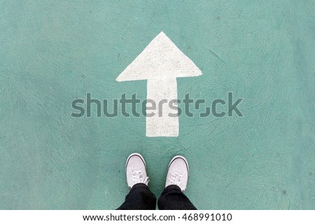  shoes standing on the concrete floor and white direction sign to go ahead Royalty-Free Stock Photo #468991010
