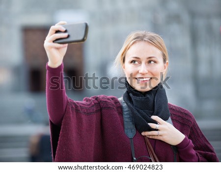 Young charming  girl taking picture with her phone in the town