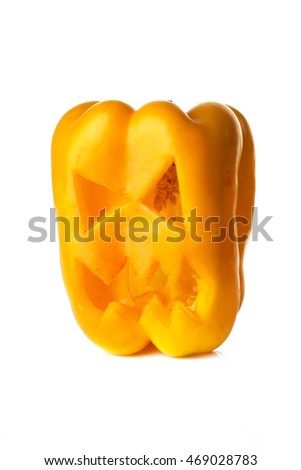 Food art creative concept. Halloween scary face carved into yellow capsicum vegetables isolated over a white background.