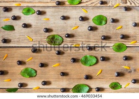 Aronia berries (black chokeberry), calendula petals and leaves  on wooden background in rustic style. Top view.
