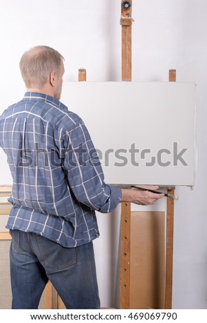 An artist in studio thinking in front of canvas
