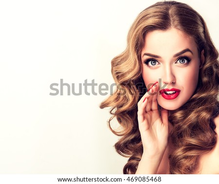 Beautiful girl with bright makeup and curly hair   telling a secret .Portrait  young happy woman who is calling to someone .Funny girl model  whispering about something. Expressive facial expressions Royalty-Free Stock Photo #469085468