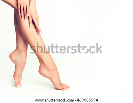 Perfect clean female feet . Beautiful and elegant groomed girl's hand touches her feet . Spa ,scrub and foot care . Royalty-Free Stock Photo #469085594