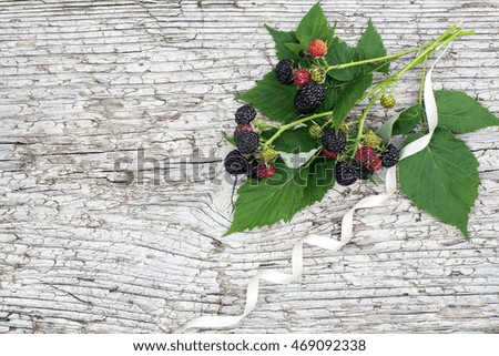 Bunch of black raspberries (Rubus occidentalis) and white ribbon on the old wooden background with space for text 
