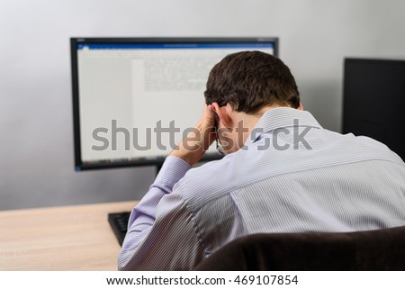 tired and resigned man working on computer in office, writing text - stock photo