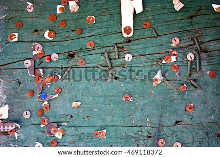 Rotten pins on green scratched wooden board with torn peaces of old announcements and notices
